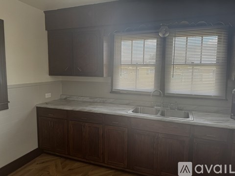 A kitchen with dark wood cabinets and a marble countertop.