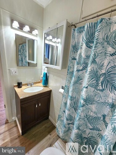 A bathroom with a sink, mirror, and shower curtain.