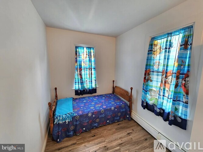 A bedroom with a bed, wooden headboard, and a window with curtains.