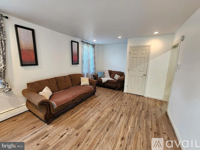 A living room with a brown couch and a wooden floor.