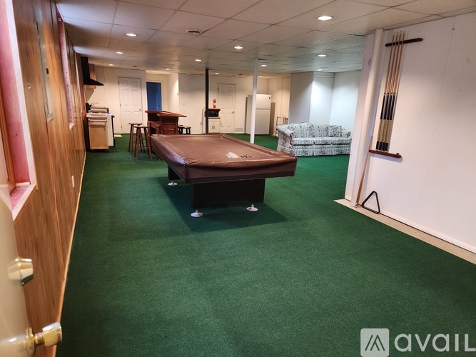 A room with a green carpet and a bed in the center.