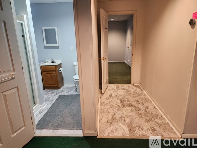 A hallway with a carpeted floor and a doorway leading to another room.