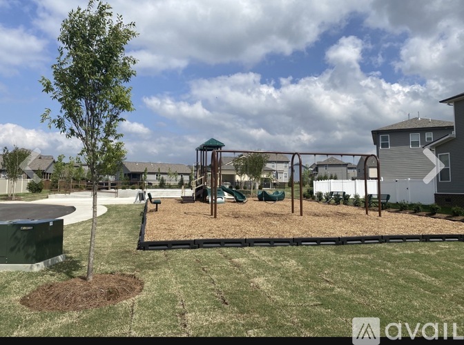 A playground with a swing set and a tree in the foreground.
