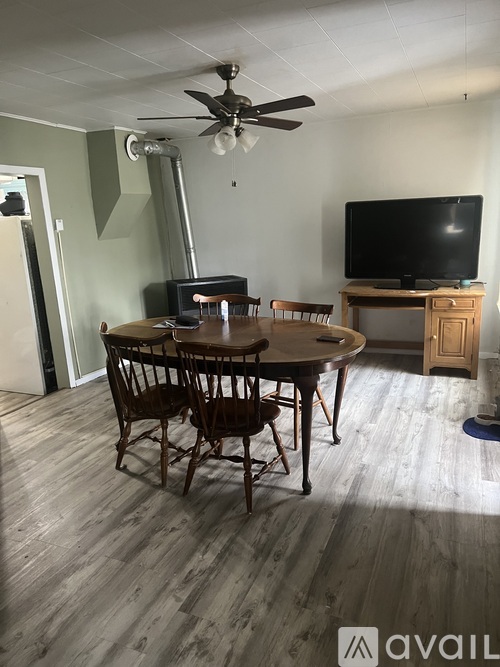A room with a wooden table and chairs and a television.