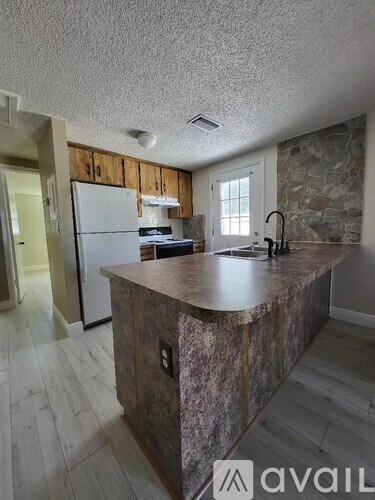 A kitchen with a stone counter and wooden cabinets.