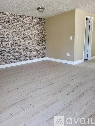 A room with wooden flooring and a stone wall.