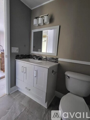 A bathroom with a toilet, sink, and mirror.