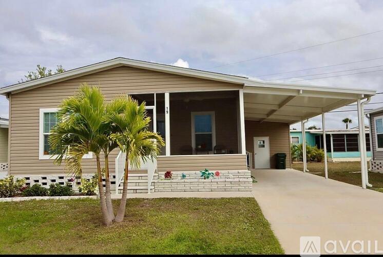 A house with a porch and a palm tree in front.