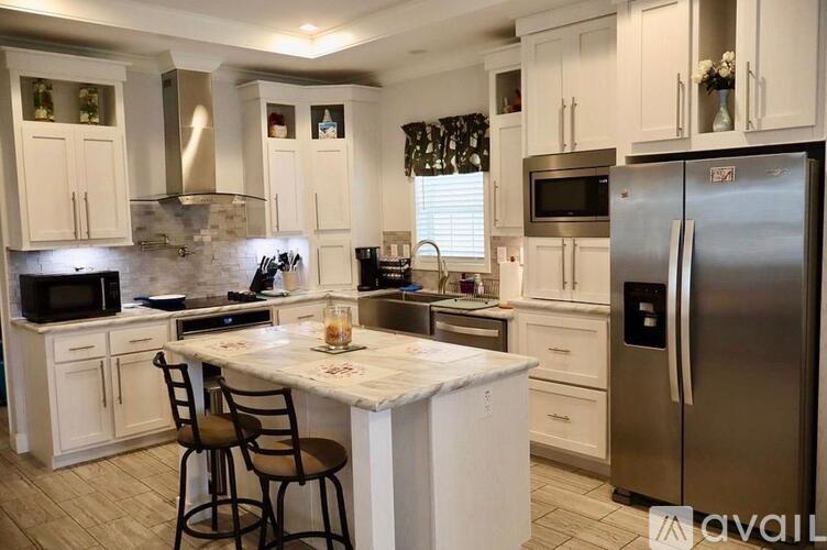 A kitchen with white cabinets and a marble island.
