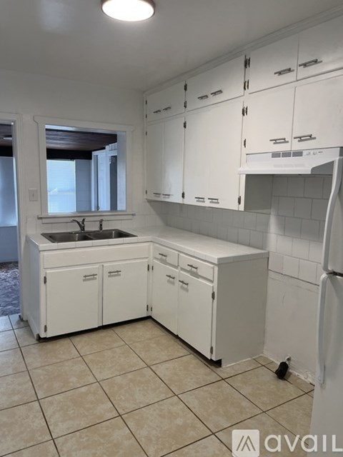 A kitchen with white cabinets and a tiled floor.
