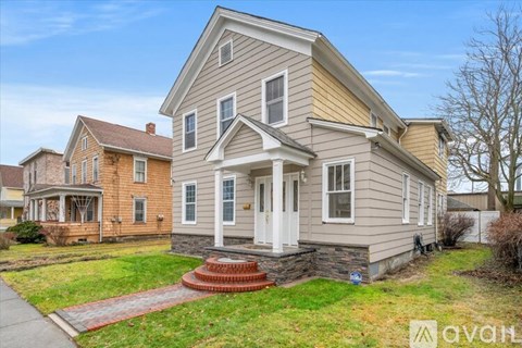 A two-story house with a front porch and a red brick walkway.
