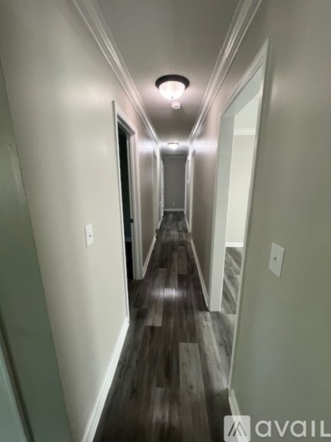 A long hallway with wood floors and white walls.