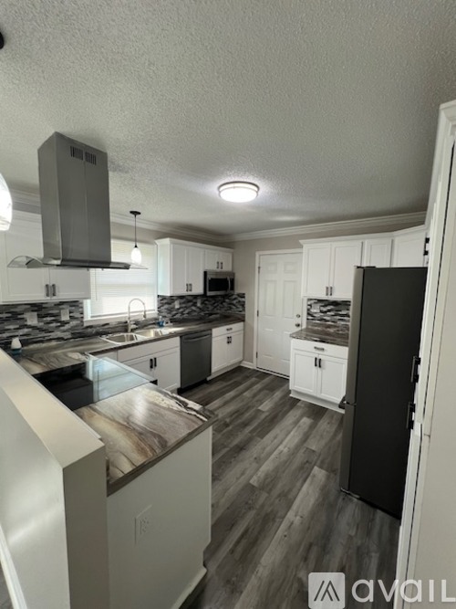 A kitchen with white cabinets and a black refrigerator.