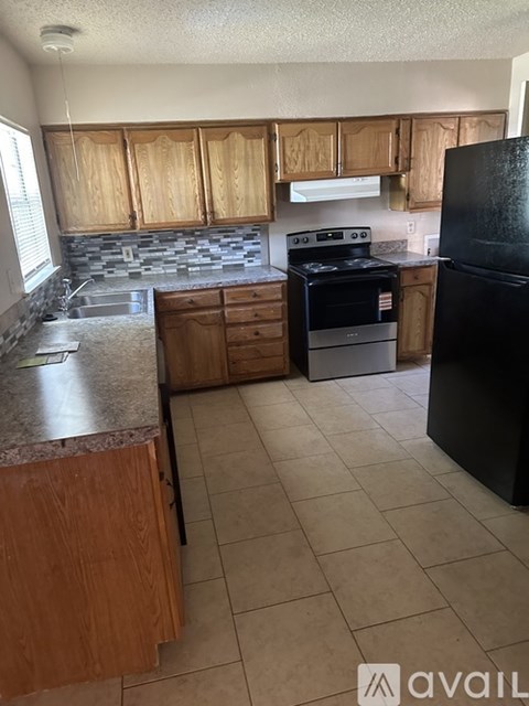 A kitchen with wooden cabinets and black appliances.