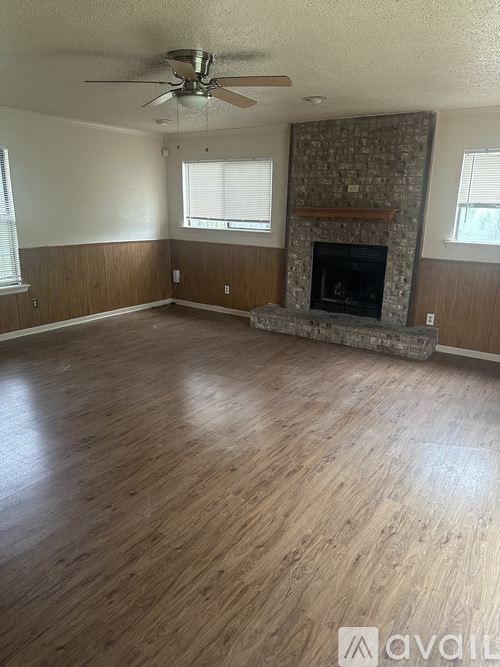 A room with a fireplace and wood flooring.