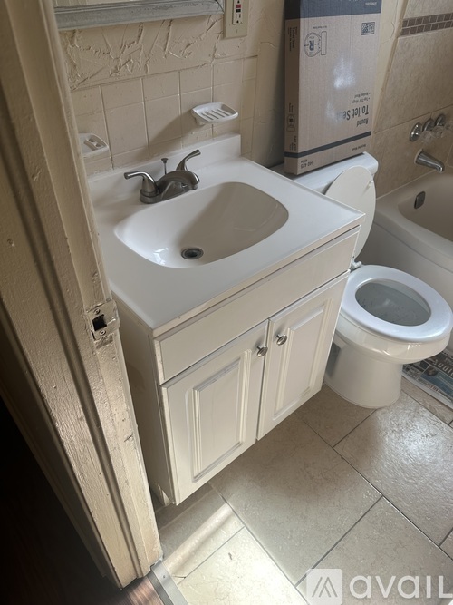 A bathroom with a toilet, sink, and a box on the floor.