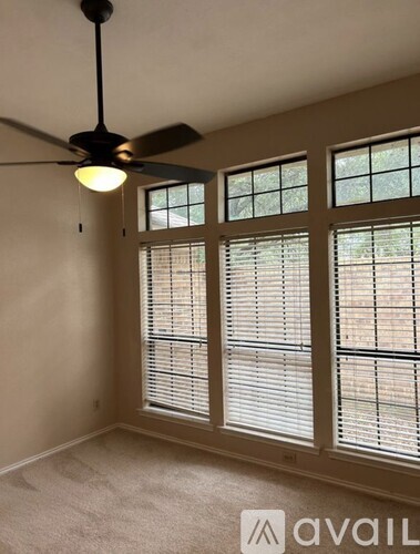 A room with a ceiling fan and a window with blinds.