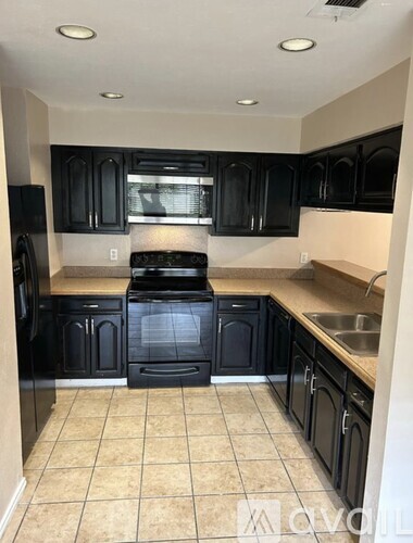 A kitchen with black cabinets and a black stove top oven.