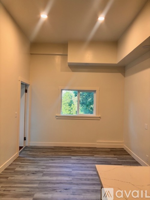 A room with a window and a wooden floor.