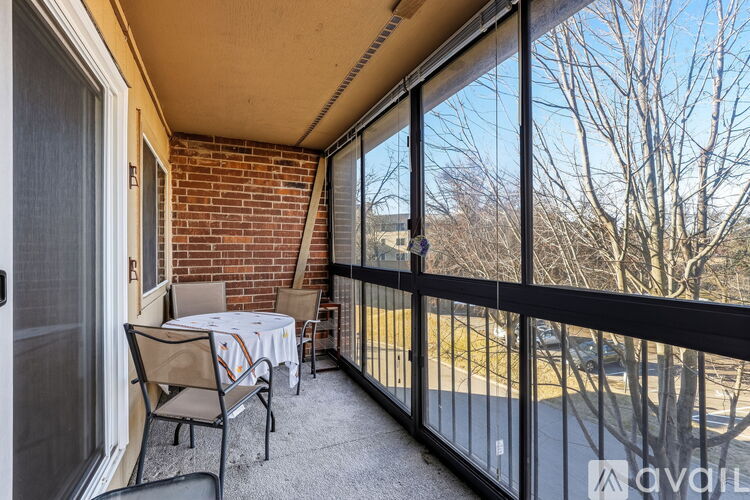 A balcony with a table and chairs overlooking a tree.