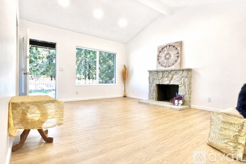 A living room with a fireplace and a chair with a gold blanket.