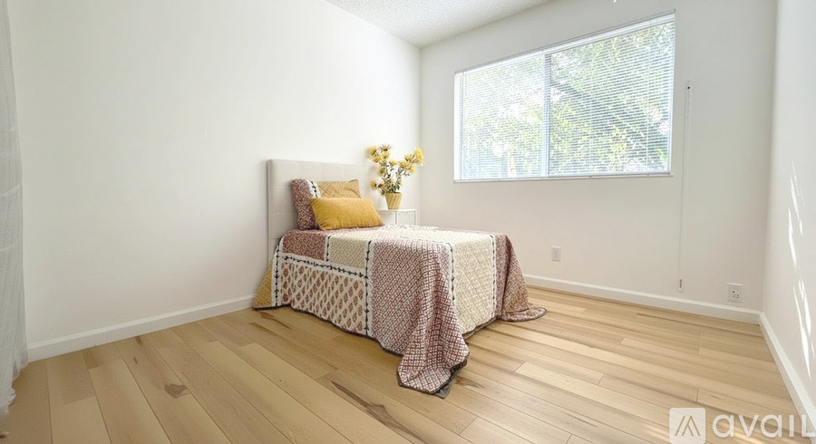 A bedroom with a bed covered in a pink and white blanket.