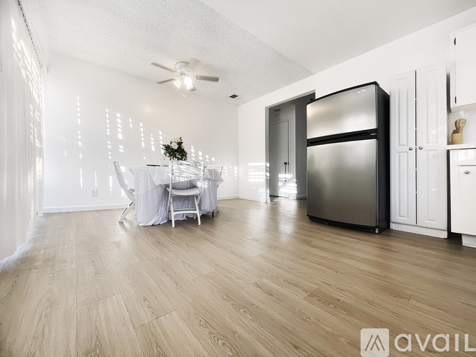 A modern kitchen with a wooden floor and a dining area with a table set for two.