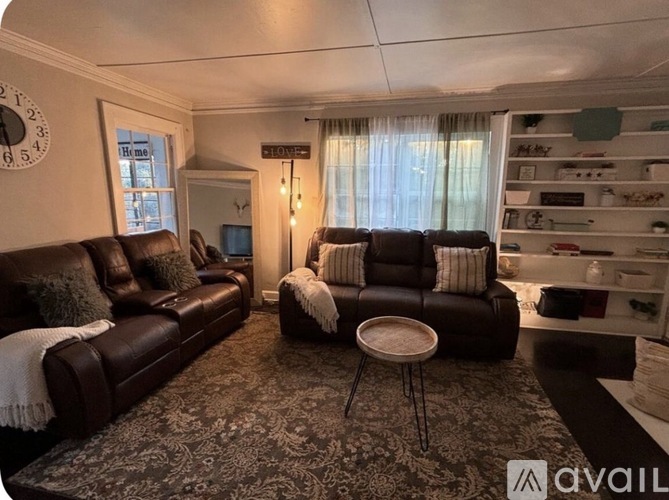 A living room with a brown leather couch and a round table.