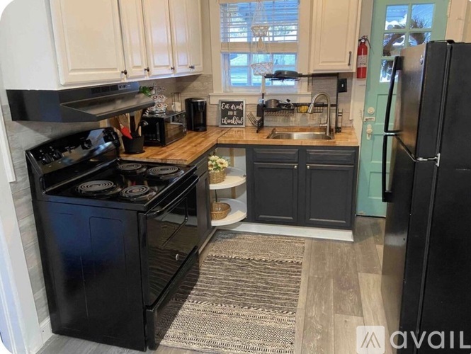 A kitchen with black appliances and a rug on the floor.