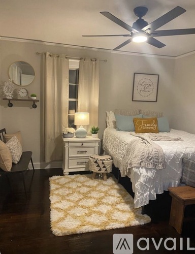 A bedroom with a bed, nightstand, chair, and rug.