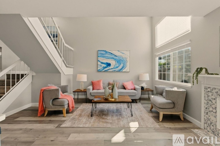 A living room with a grey couch and a painting on the wall.
