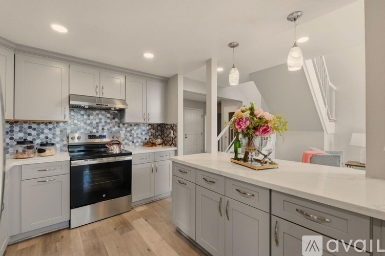 A modern kitchen with a stove top oven and a counter top with a vase of flowers on it.