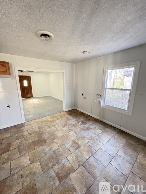 A room with a tiled floor and a window with a view of a tree.