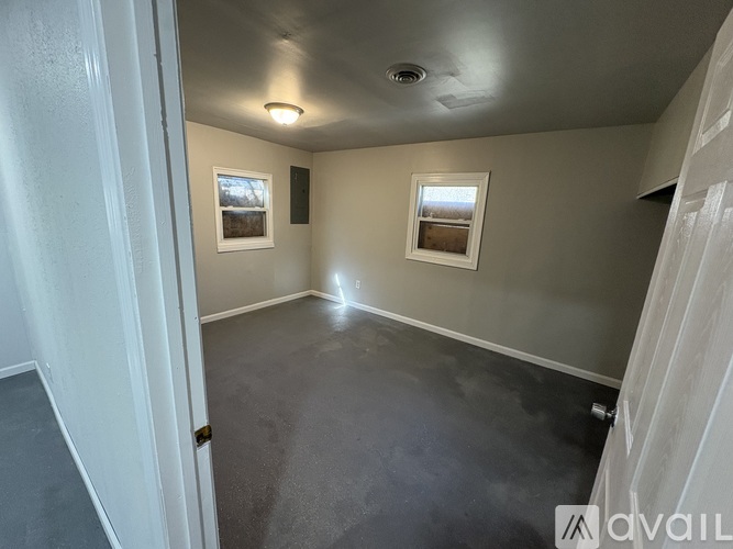 A room with grey floor and two windows.