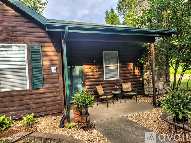 A wooden cabin with a porch and a green roof.