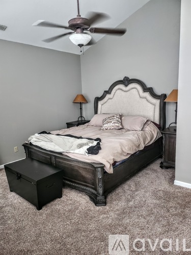 A bedroom with a bed, nightstand, and ceiling fan.