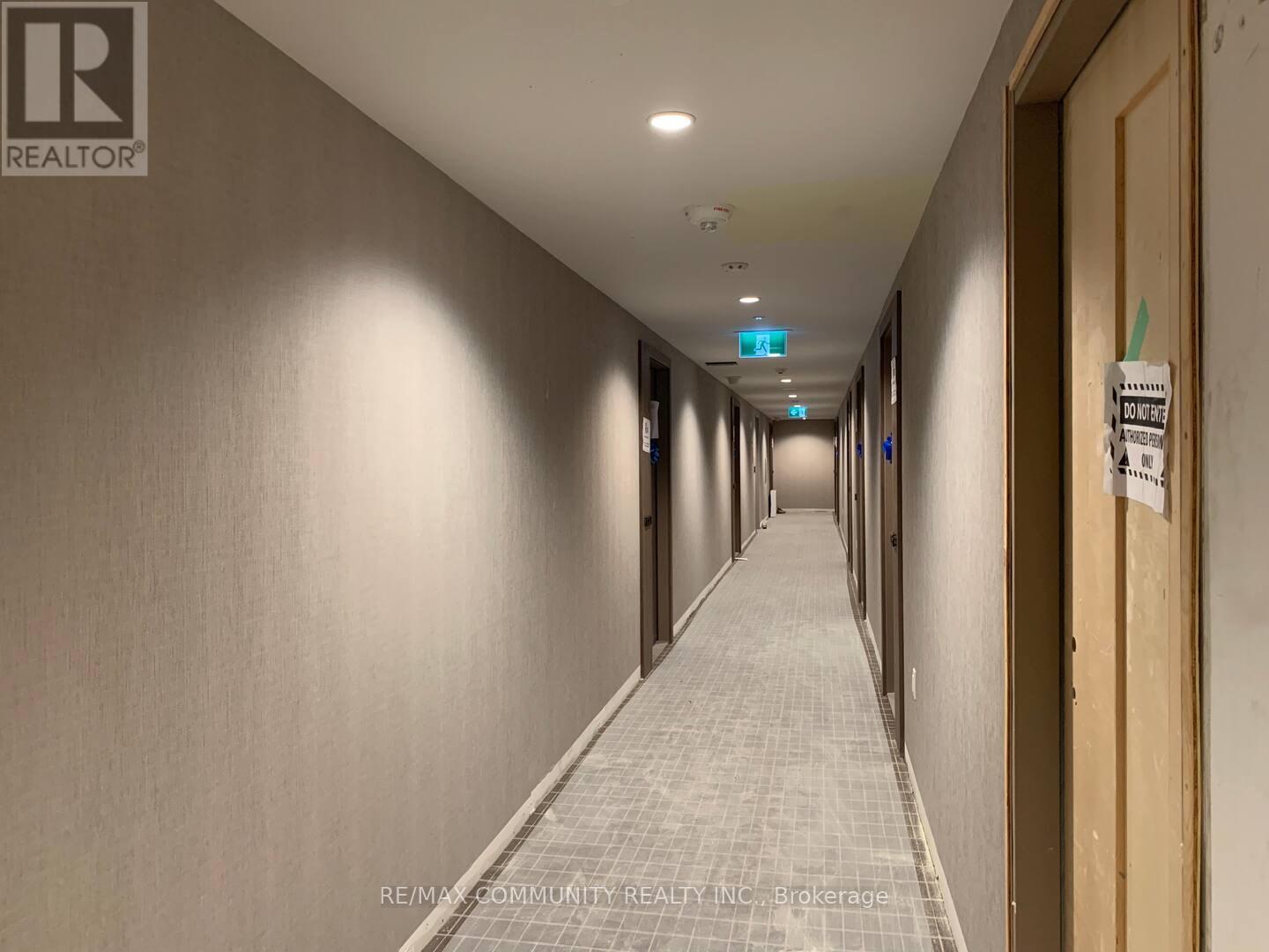 A long hallway with a sign on the wall that says "RE/MAX COMMUNITY REALTY INC Brokerage".