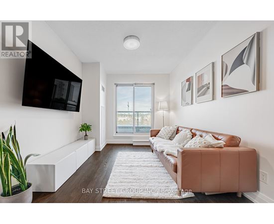 A living room with a brown couch and a flat screen TV mounted on the wall.