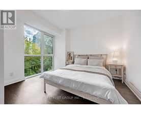 A bedroom with a large bed and a view of the outdoors through a sliding glass door.