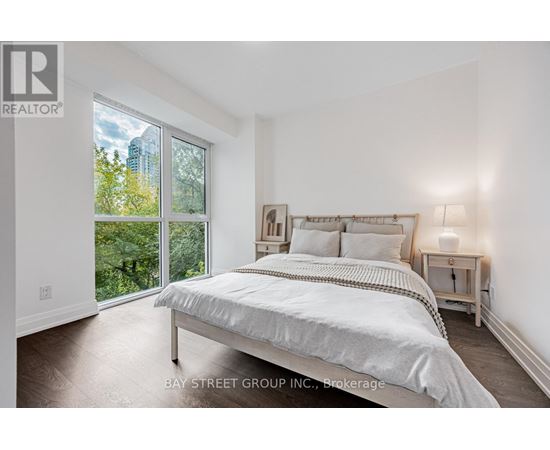 A bedroom with a large bed and a view of the outdoors through a sliding glass door.
