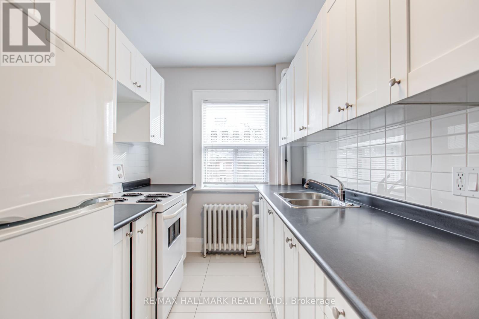 A kitchen with white cabinets and a black countertop.