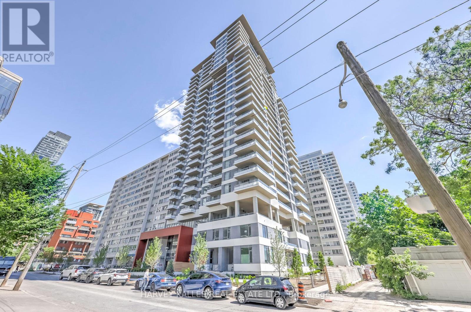 A tall residential building with a parking lot in front.