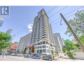 A tall residential building with a parking lot in front.