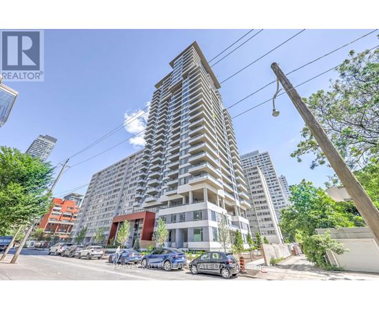 A tall residential building with a parking lot in front.