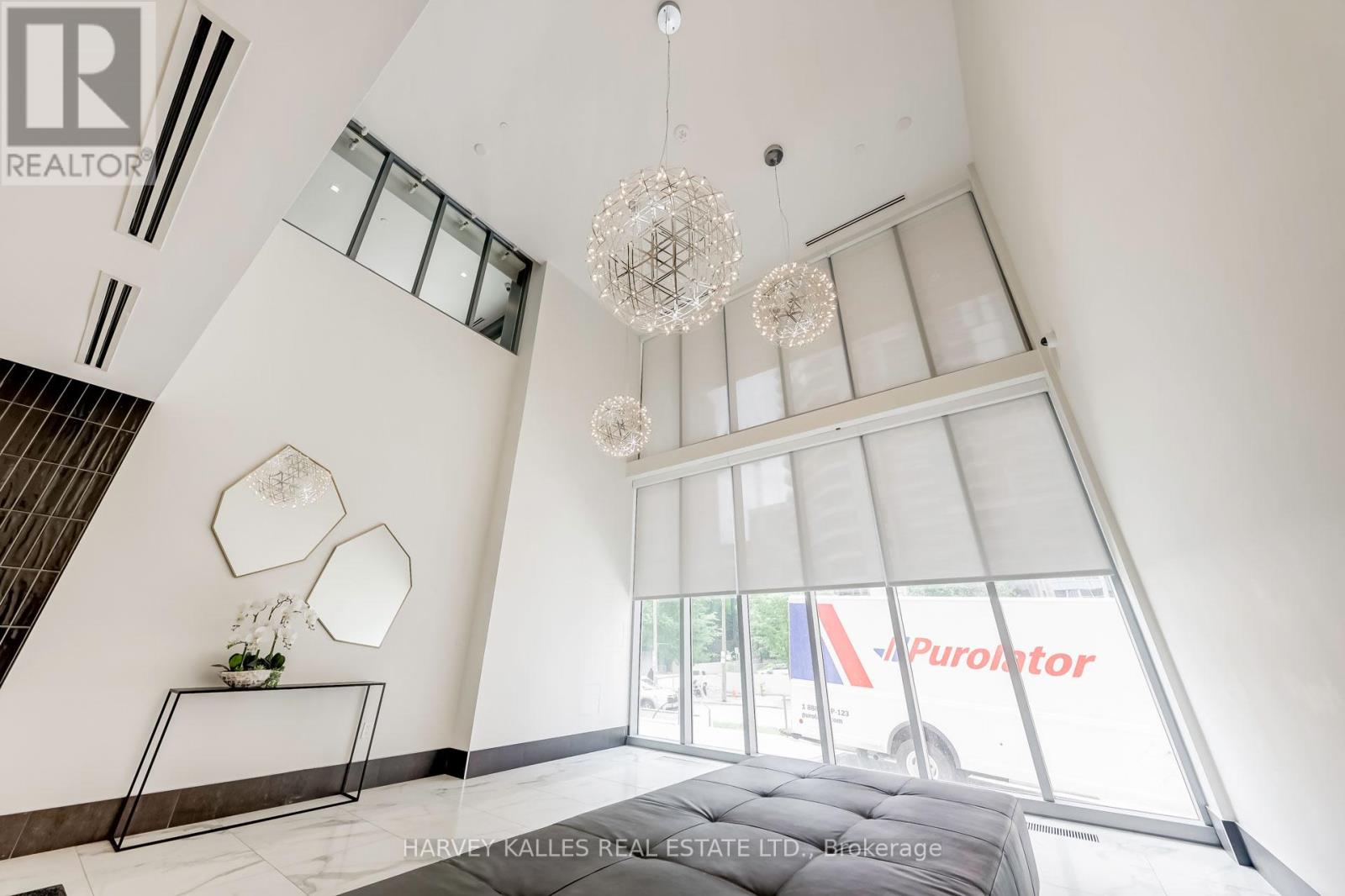 A large, modern living room with a staircase and a chandelier.