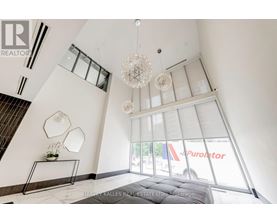 A large, modern living room with a staircase and a chandelier.