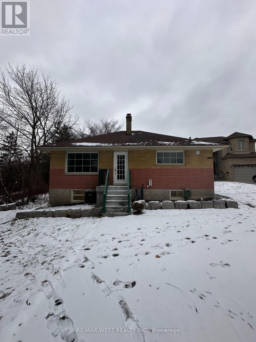 A house with a yellow and red exterior is surrounded by snow.