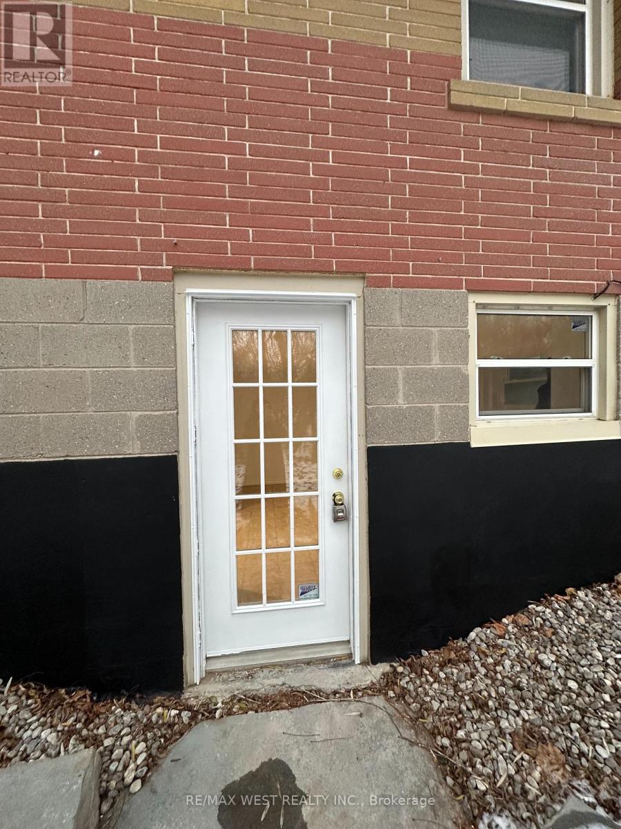 A white door with a glass panel is set in a brick wall.