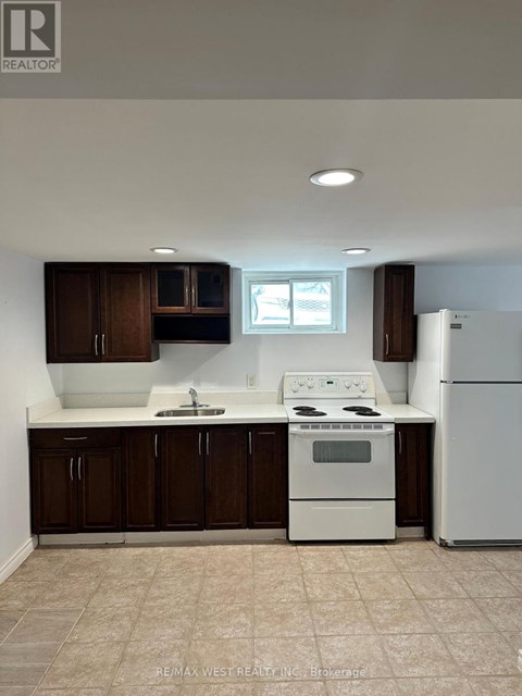 A white stove and refrigerator in a kitchen with brown cabinets.