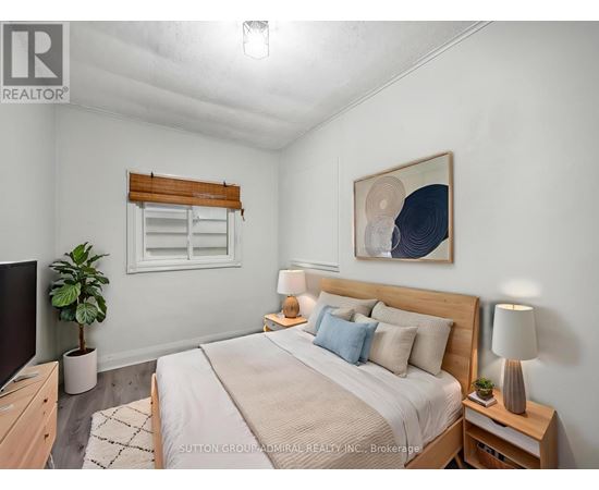 A bedroom with a large bed, a potted plant, and a painting on the wall.